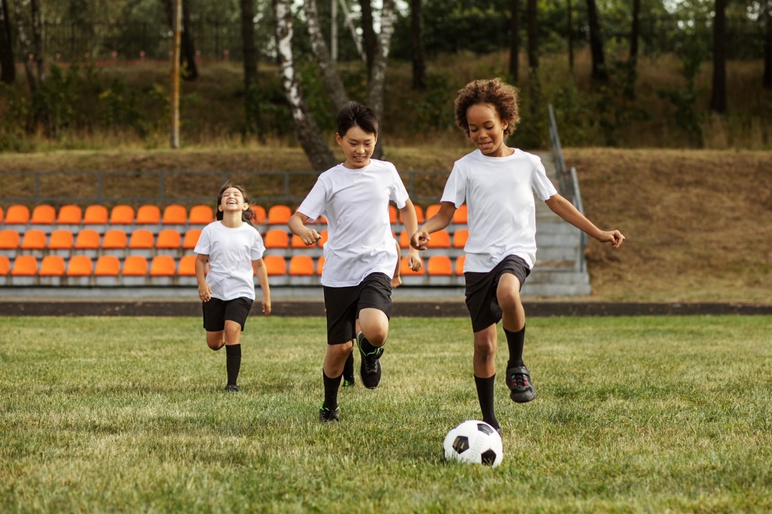 Three children smile while playing soccer