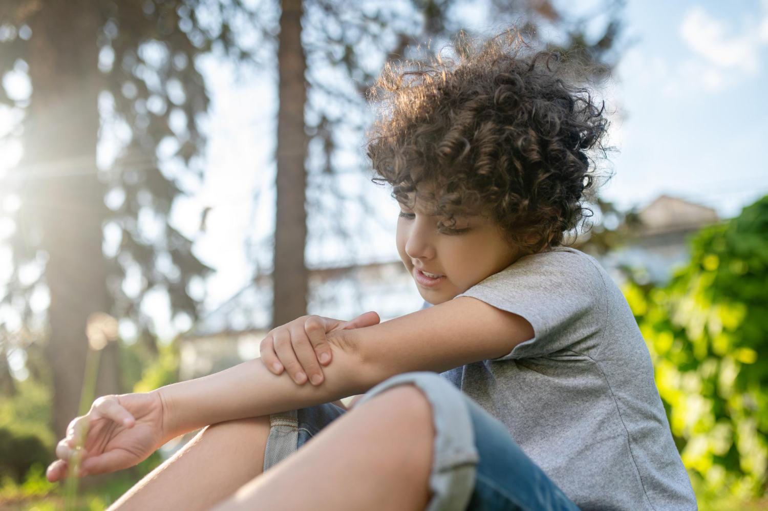 Child with nursemaid's elbow holding their arm while sitting int he grass